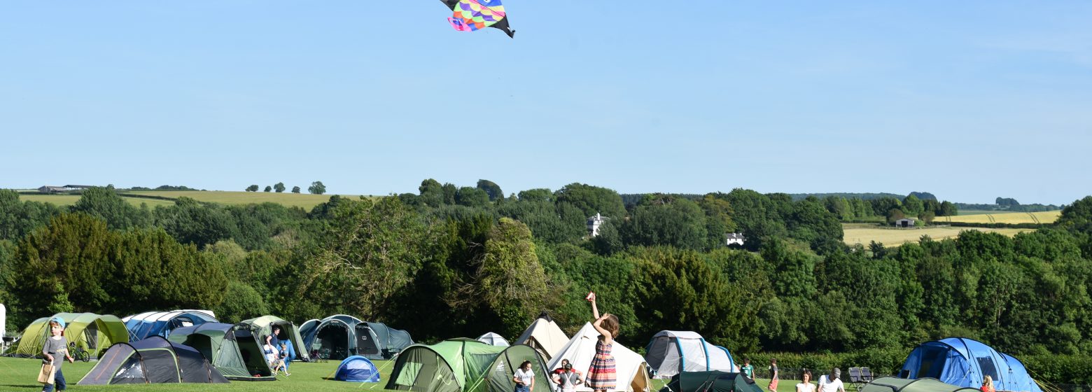 children flying a kite above tents
