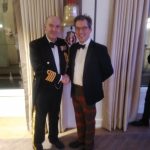 Two men in tuxedos, one with a Naval jacket and one in a pair of tartan trousers
