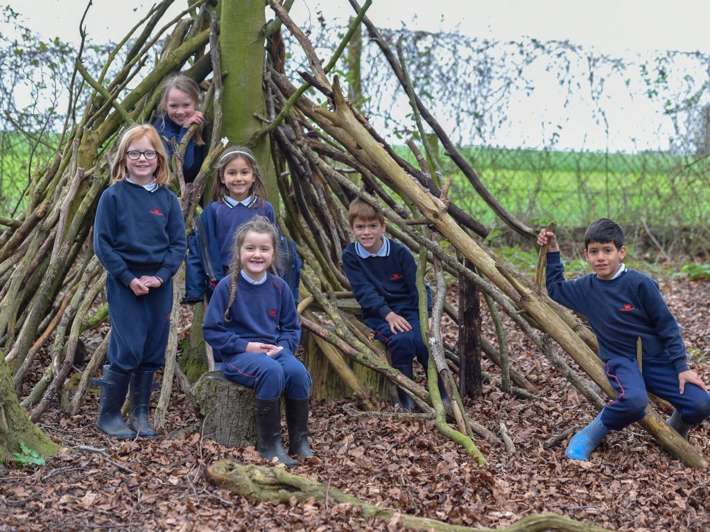 group of children in front of a wooden den