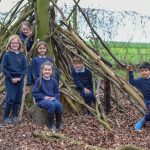 group of children in front of a wooden den