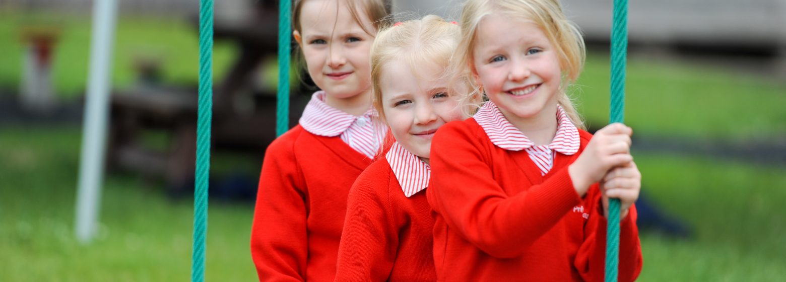 three young school girls sitting outside