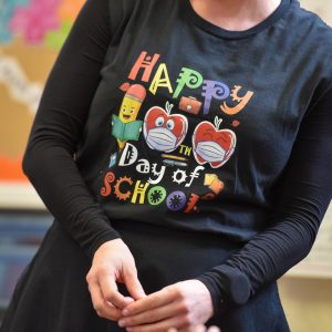 A teacher wearing a t-shirt that says 'Happy Day of School'