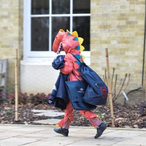A child walking to school with their backpack, dressed as a dragon.