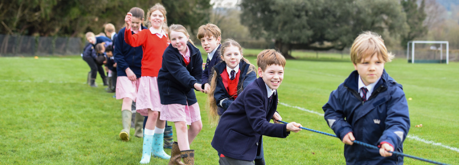 Children playing tug of war across the grass