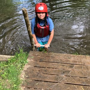 Child wearing an inflatable as they exit the water, with a helmet on their head