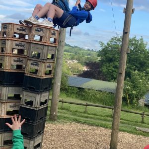 Children abseiling. They're placing their feet onto old bottle crates to balance themselves