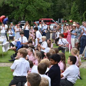 children and parents gathered on a field for a leavers party