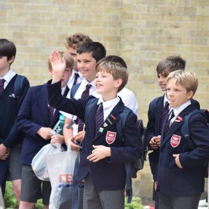 a boy from a prep school in Hampshire standing with his friends and waving